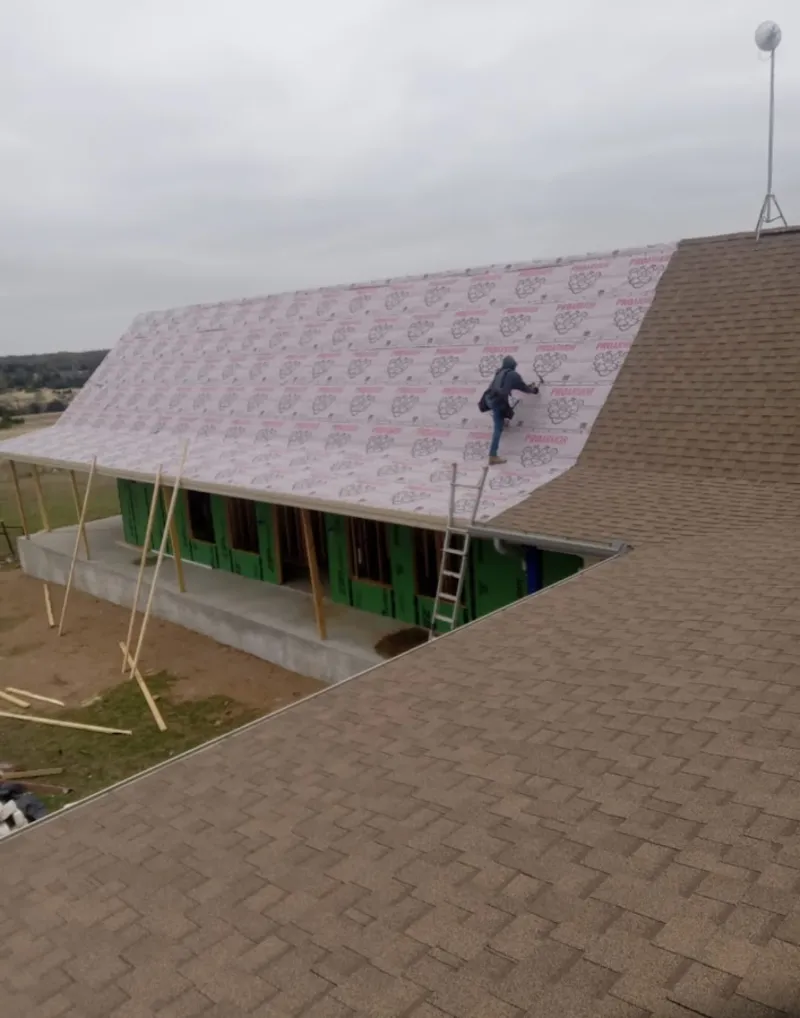 Worker preparing underlayment for a metal roof installation in Gloucester